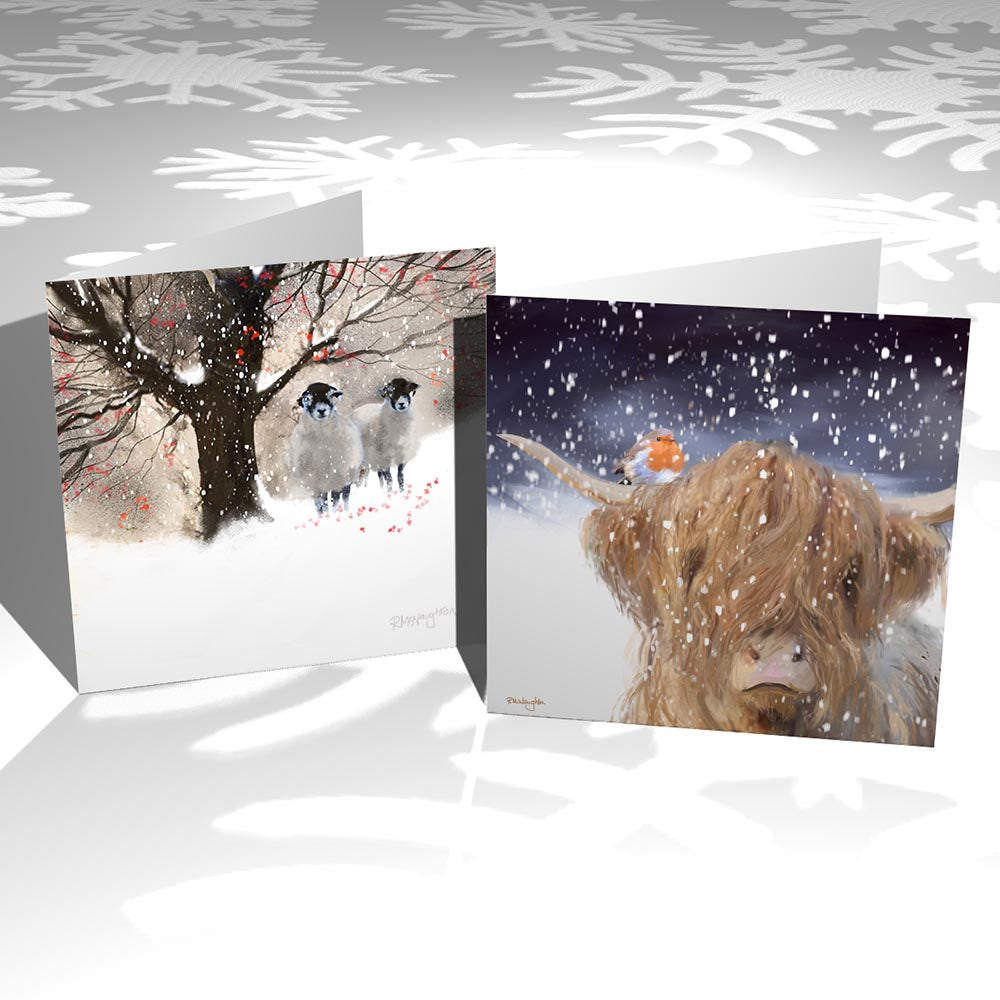 Two Christmas cards standing side by side, they are both square shape. On the left the card is a painting of two sheep standing underneath a tree, in the snow with snow falling around them. On the right the card is a painting of a highland cow and a robin resting on it's left horn. The cow is looking straight ahead with snow falling.